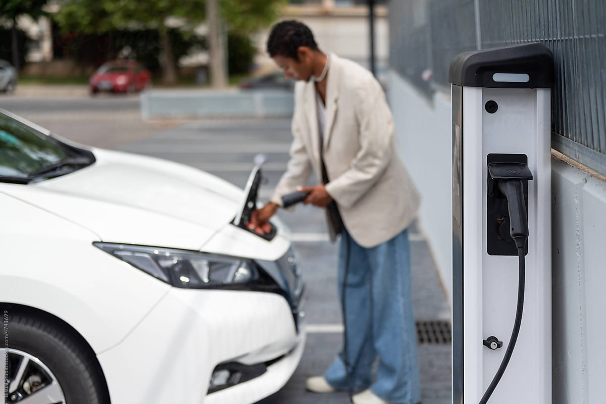 Blurred black man charging an electric car