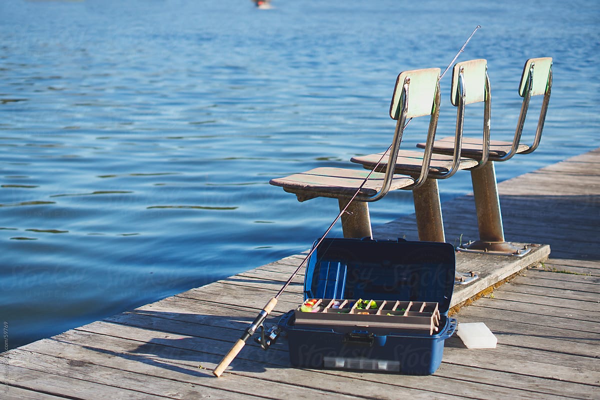 A Fishing Pole And Tackle Box Sit On A Dock Next To Old Fishing