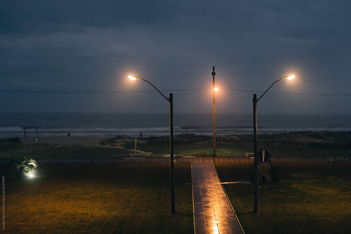 Wavy ocean in the evening with a path to it framed by two lanterns