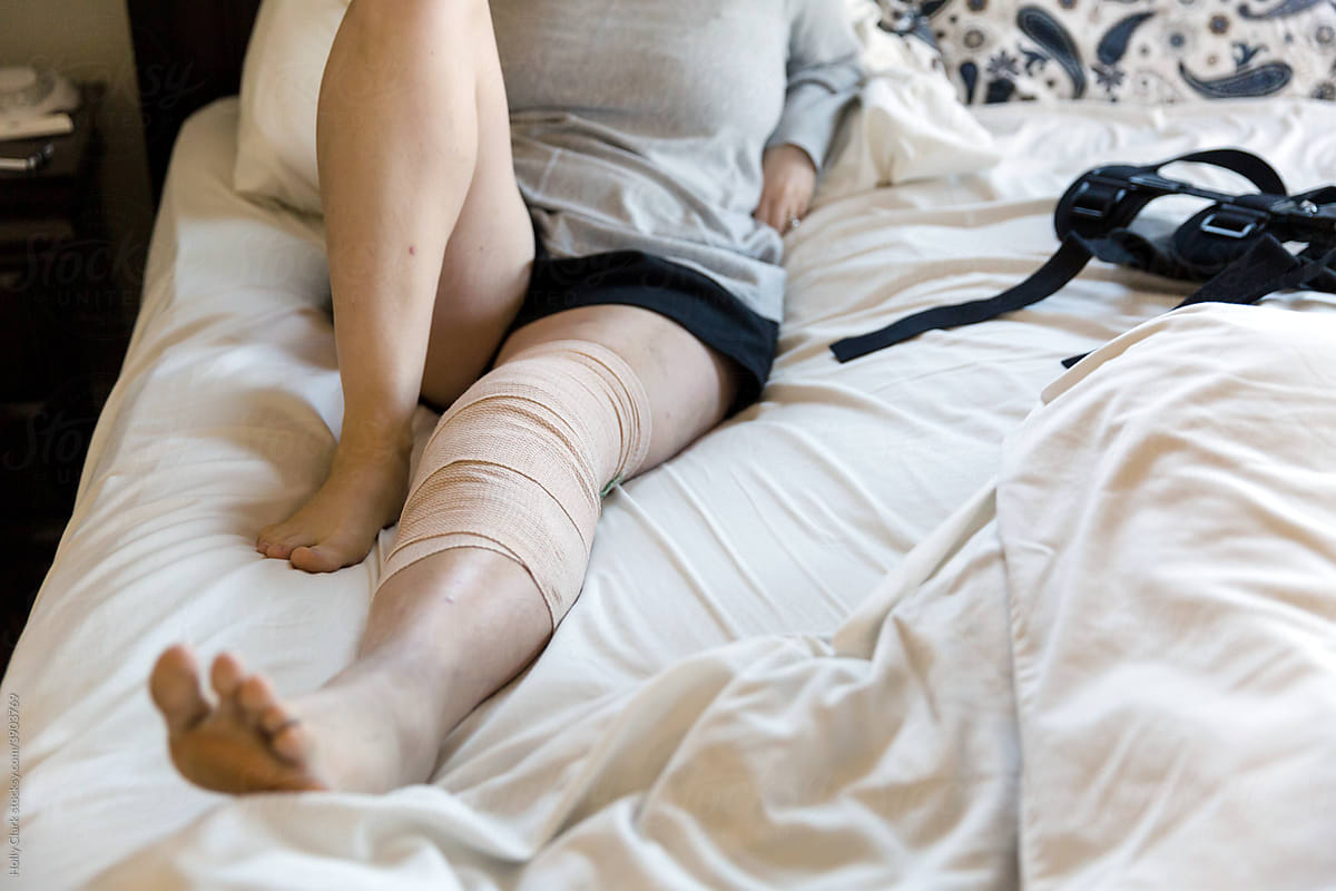 Bandaged leg on sheets in bed