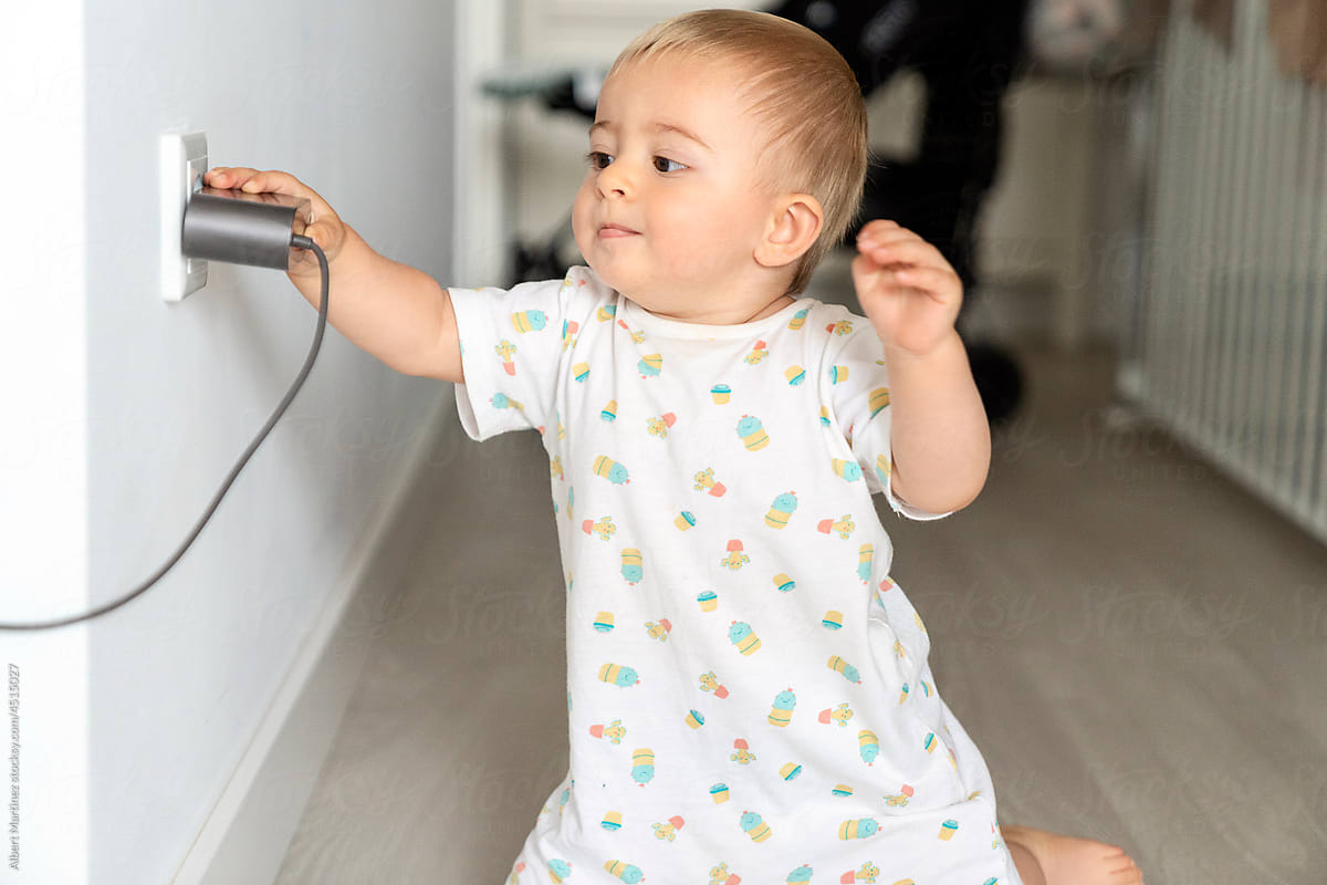 Cute baby trying to pull out charger from socket