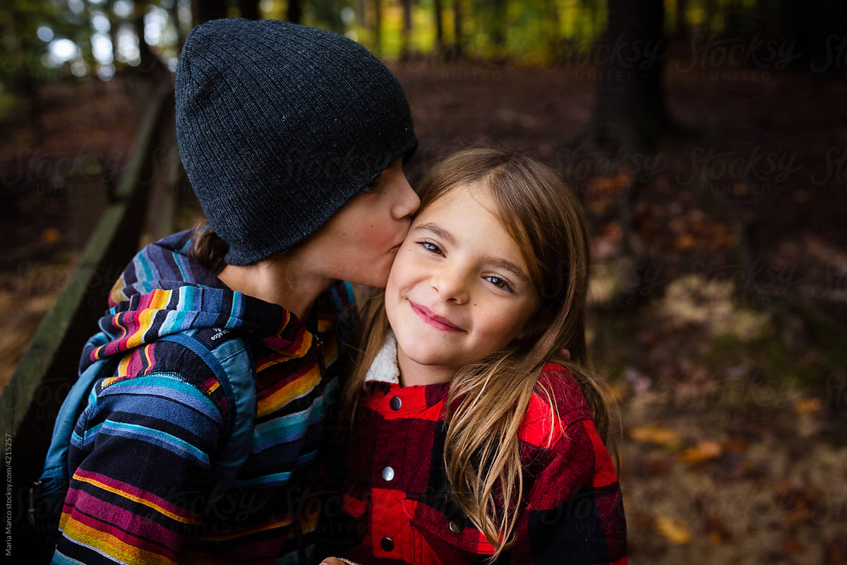 Siblings show affection while outside in fall leaves