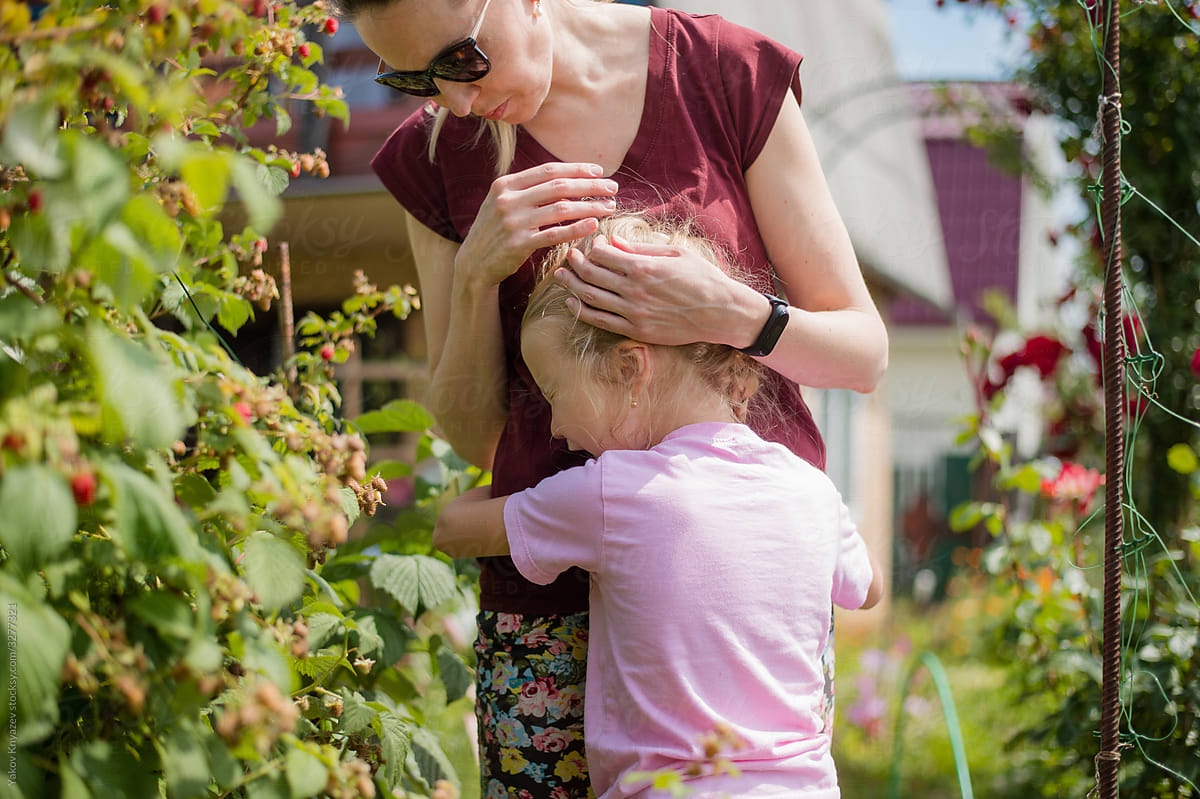 cute blonde girl cries hugging her mother in the garden