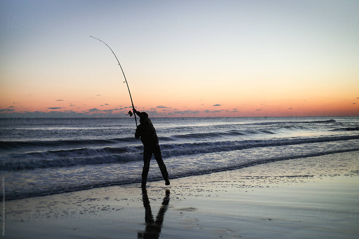 Silhouette Of Person Surf Fishing Alone On Ocean Beach With Long Rod At  Sunset by Stocksy Contributor Matthew Spaulding - Stocksy