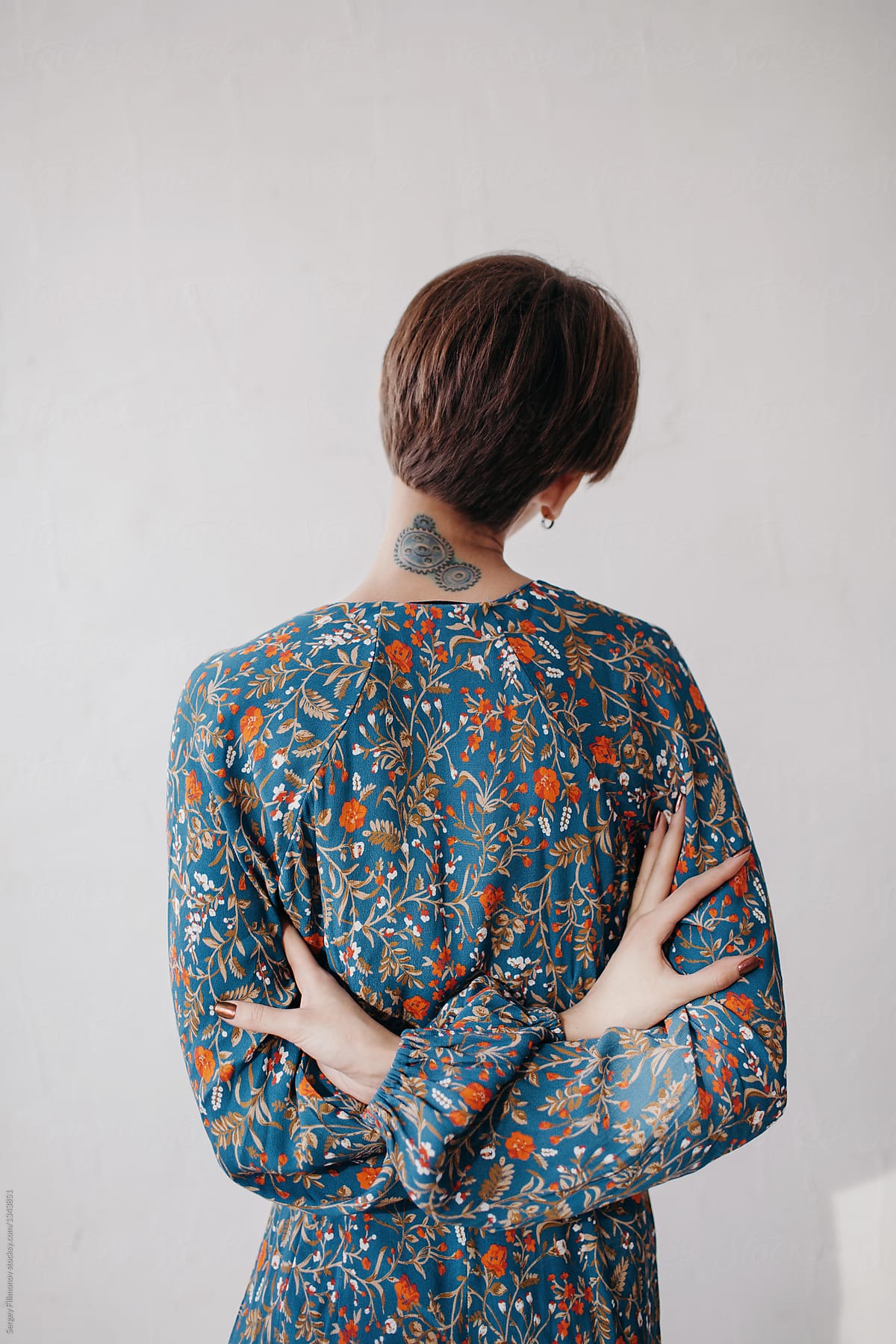Back view of brunette anonymous female in floral fress on white background
