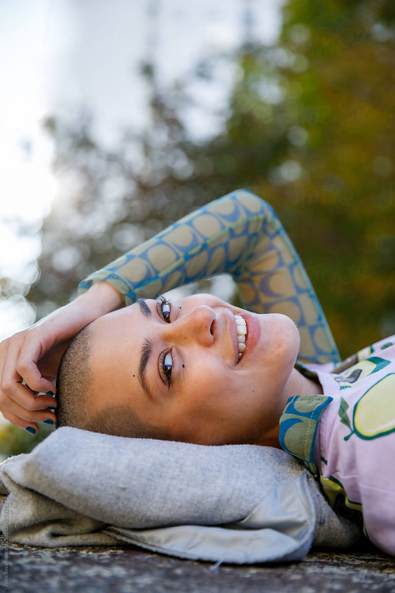 Portrait of happy woman with shaved head lying on back at park