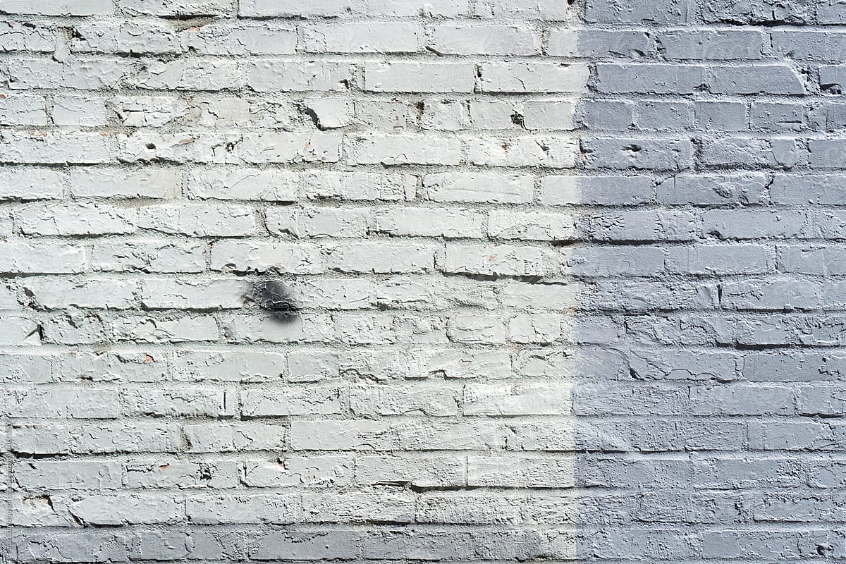 Paint covering graffiti tags on brick wall