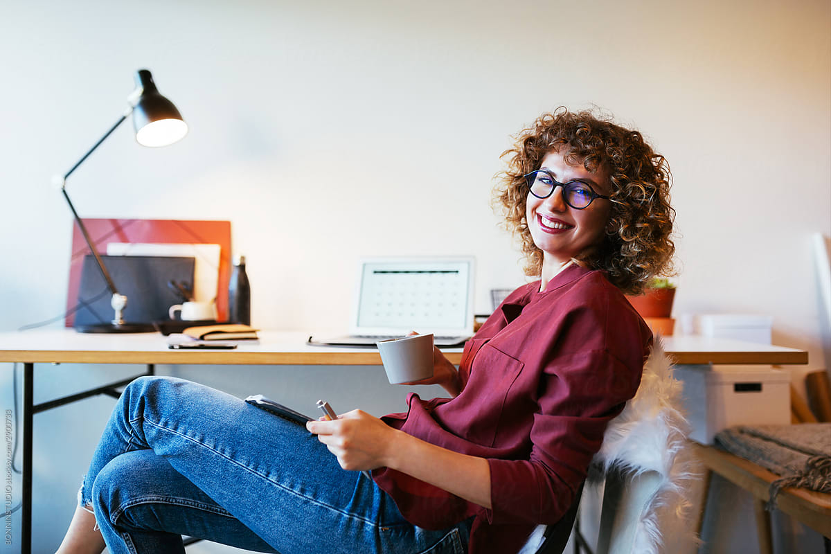 Cheerful lady enjoying hot beverage in home office