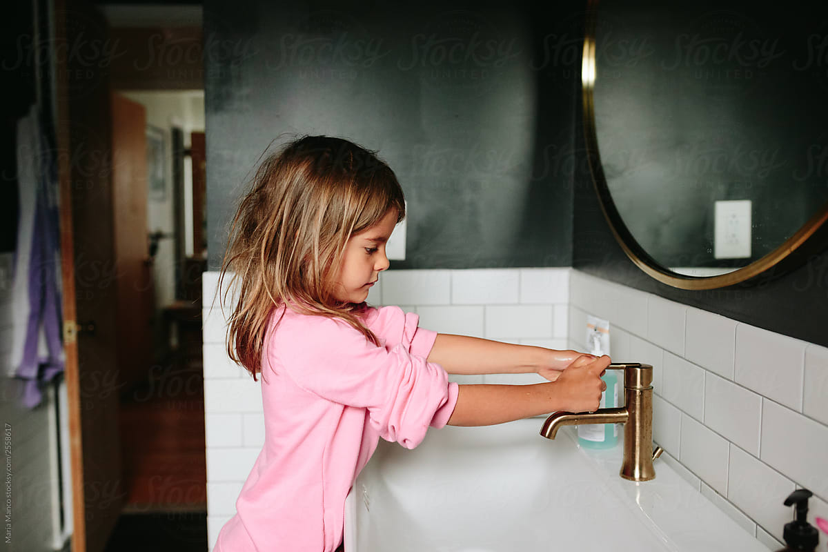 little girl washing her hands at the sink