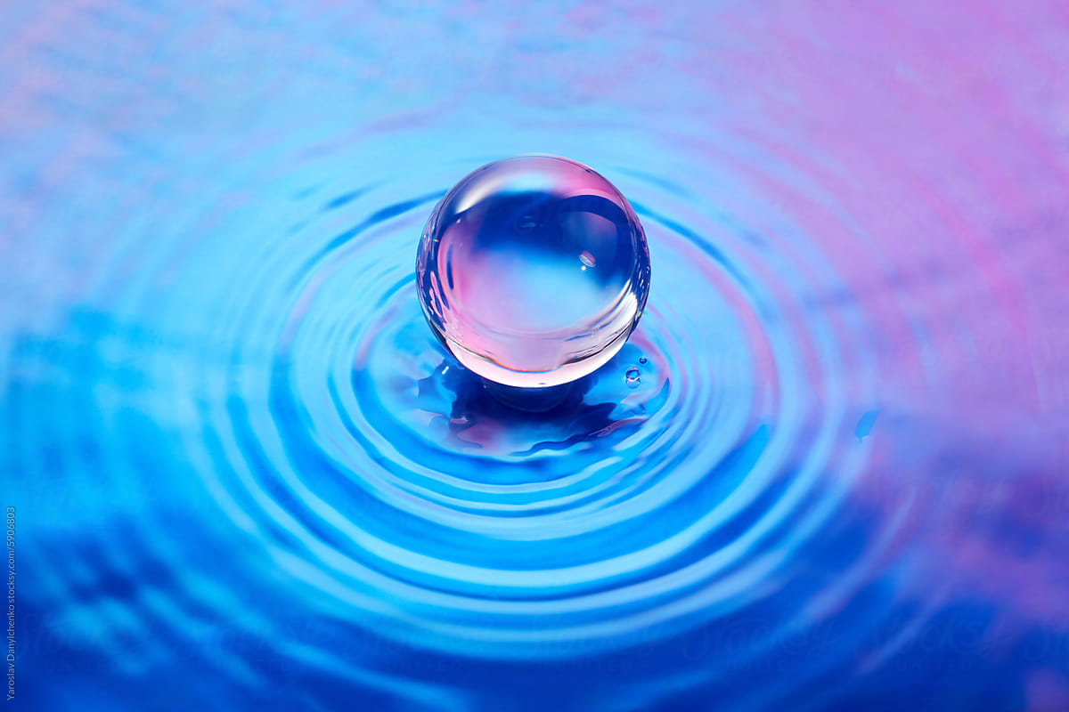 Crystal glass ball placed on water surface with iridescent gradient