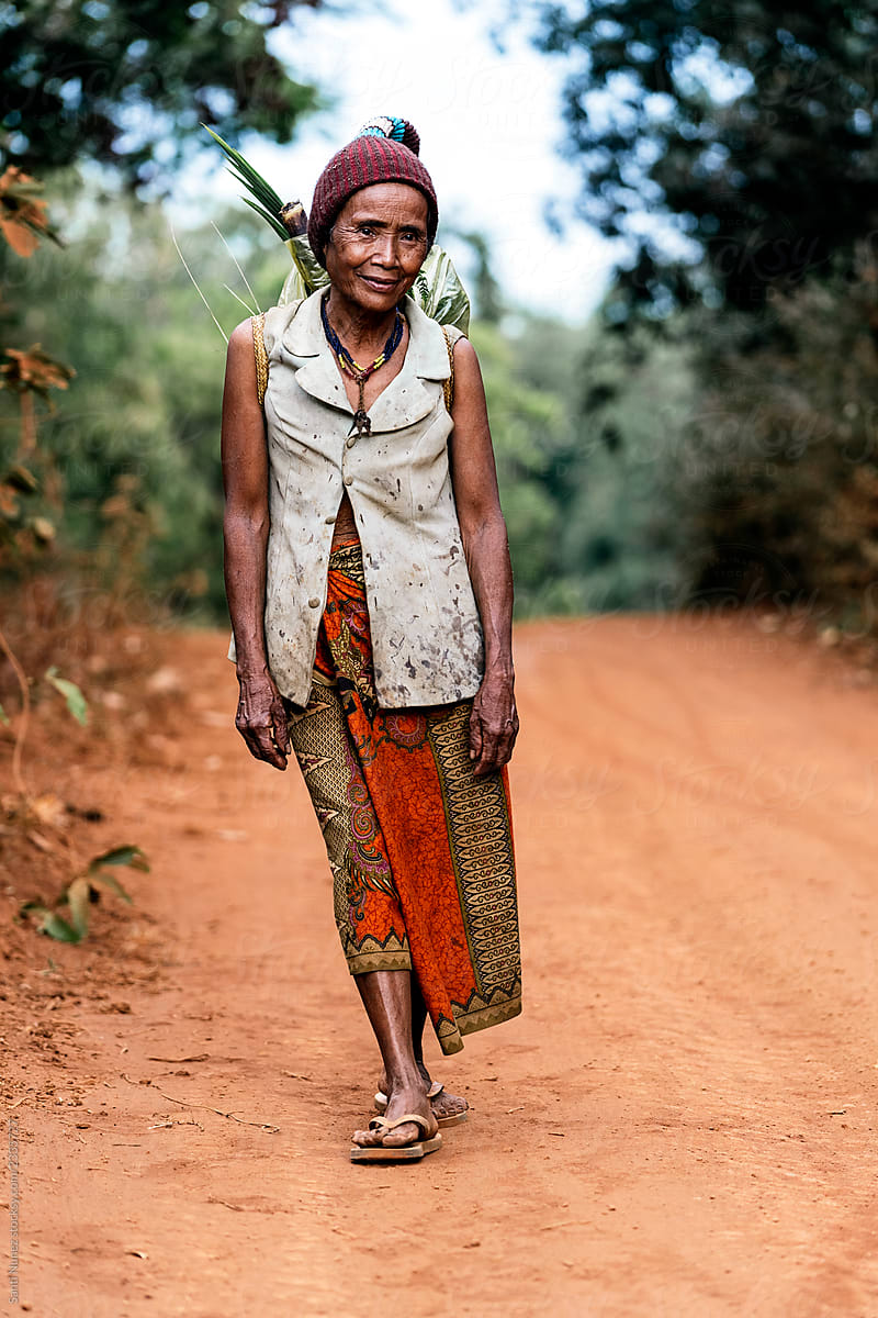 Elderly female farmer walking along road