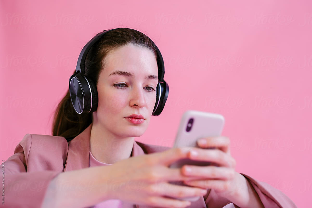 A girl chooses music on the phone to listen to it on headphones
