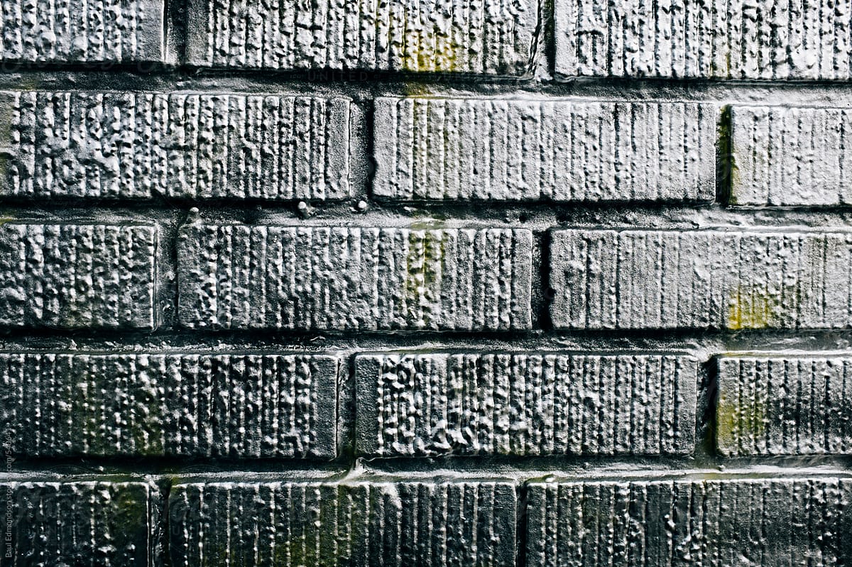 Metallic silver spray paint covering graffiti tags on brick wall