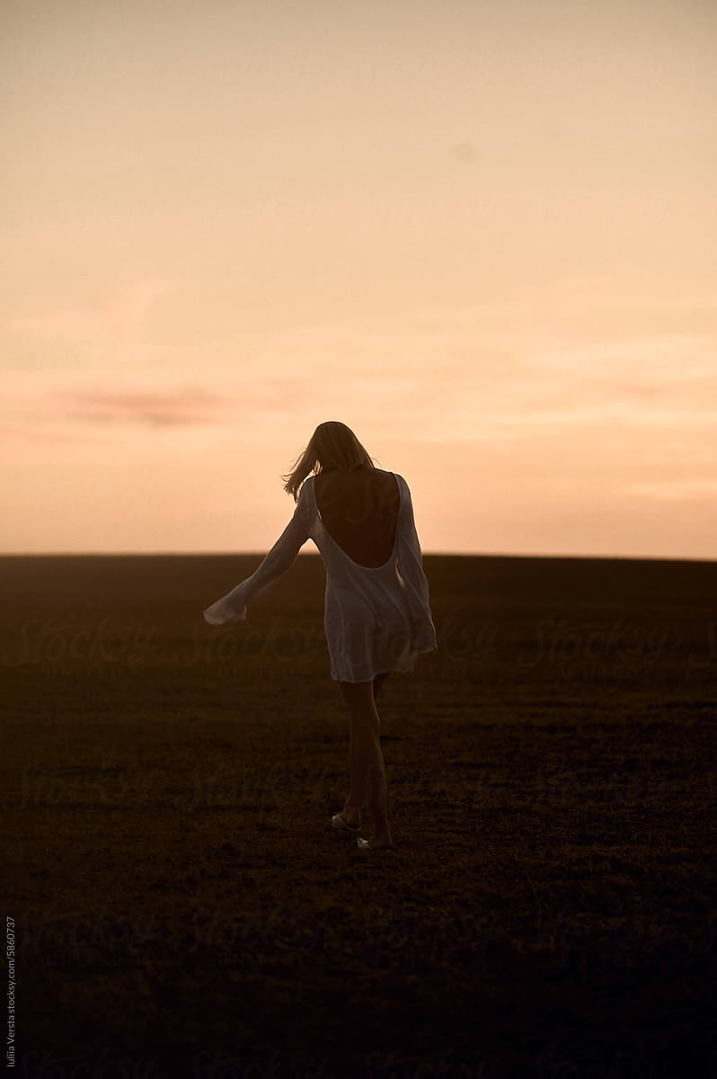 silhouette of a woman walking in the field at sunset