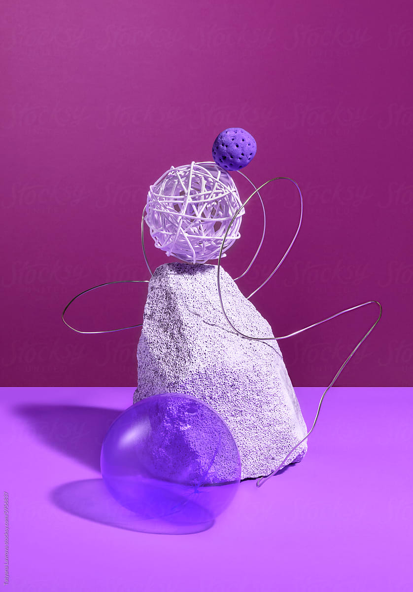 Abstract composition with spheres, wire and stones on purple backdrop