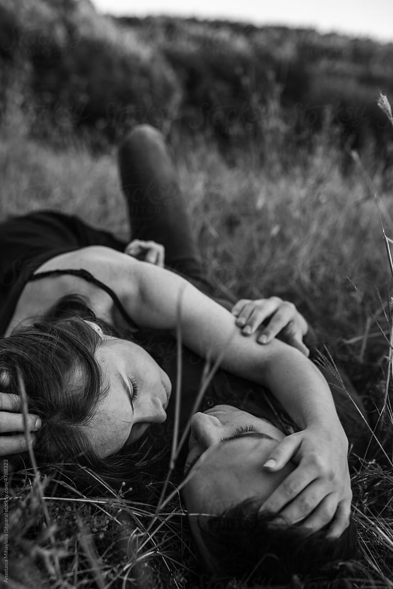 Black and white photo of couple hugging while lying on the ground