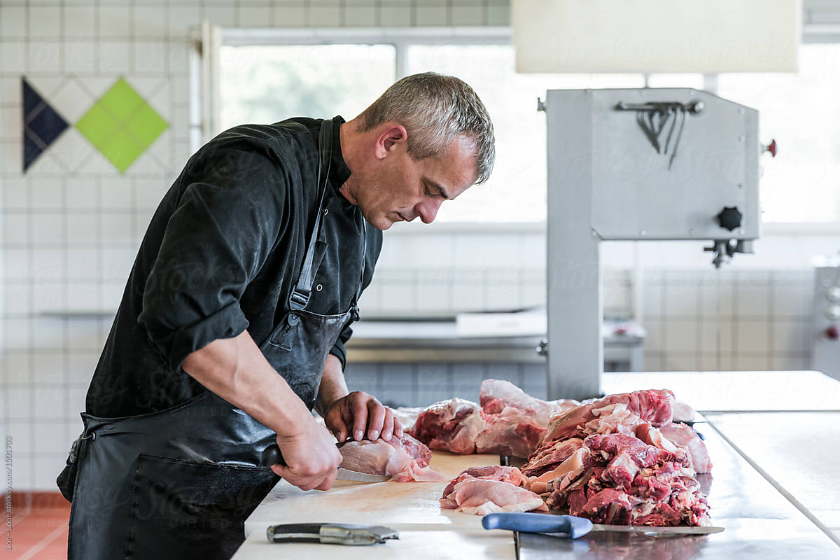 Man working as butcher cutting small pieces of meat