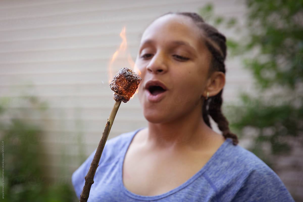 Teenager blowing out her burnt  marshmallow