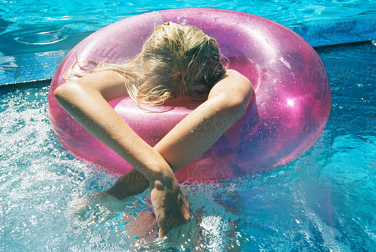 girl relaxing in pink floaty in blue pool