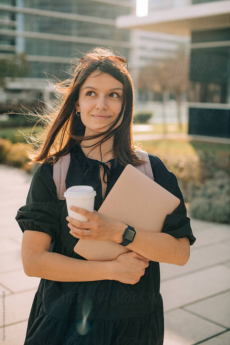Portrait of a student holding laptop and cup of coffee