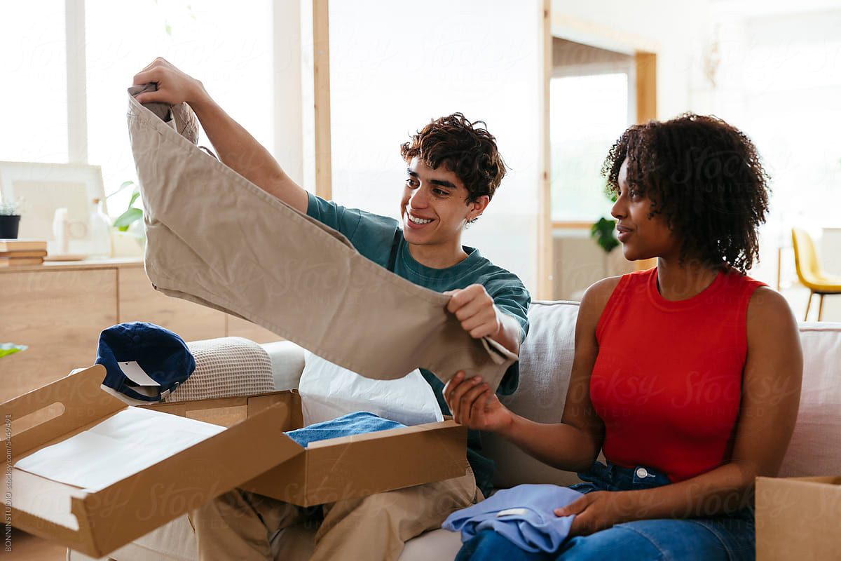 Cheerful diverse friends unpacking boxes in living room