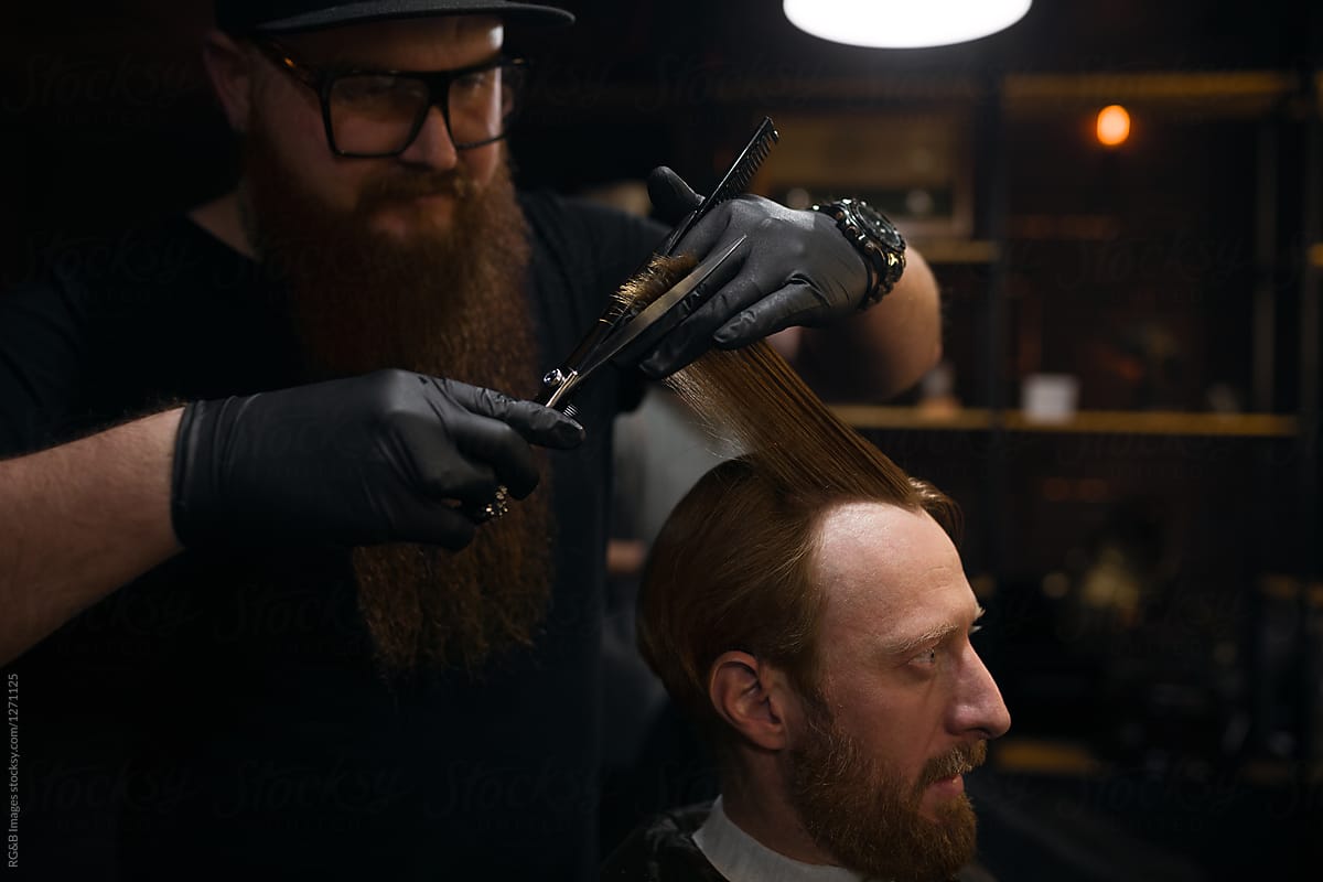 Male hairdresser cutting client\'s hair at men\'s salon