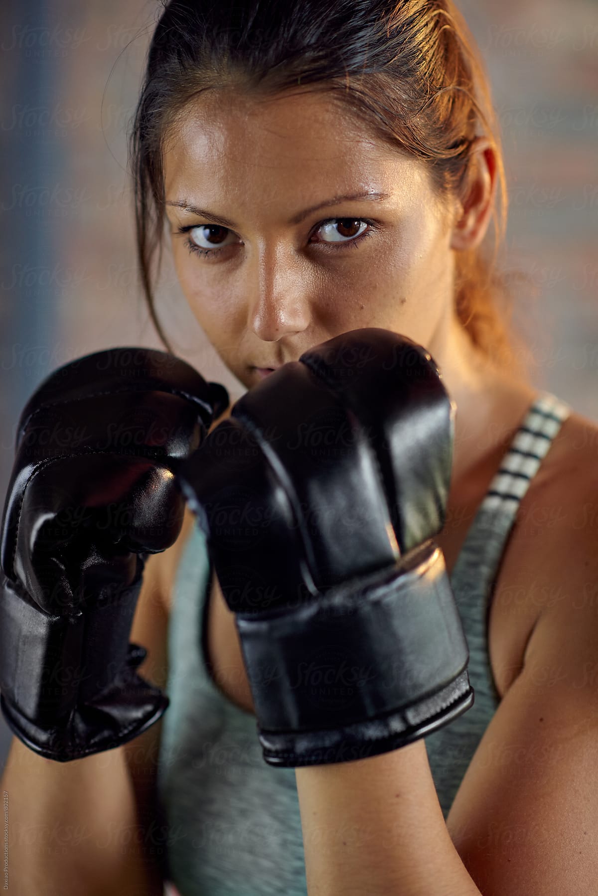 Fitness muscular lean woman boxer in black boxing punching gloves