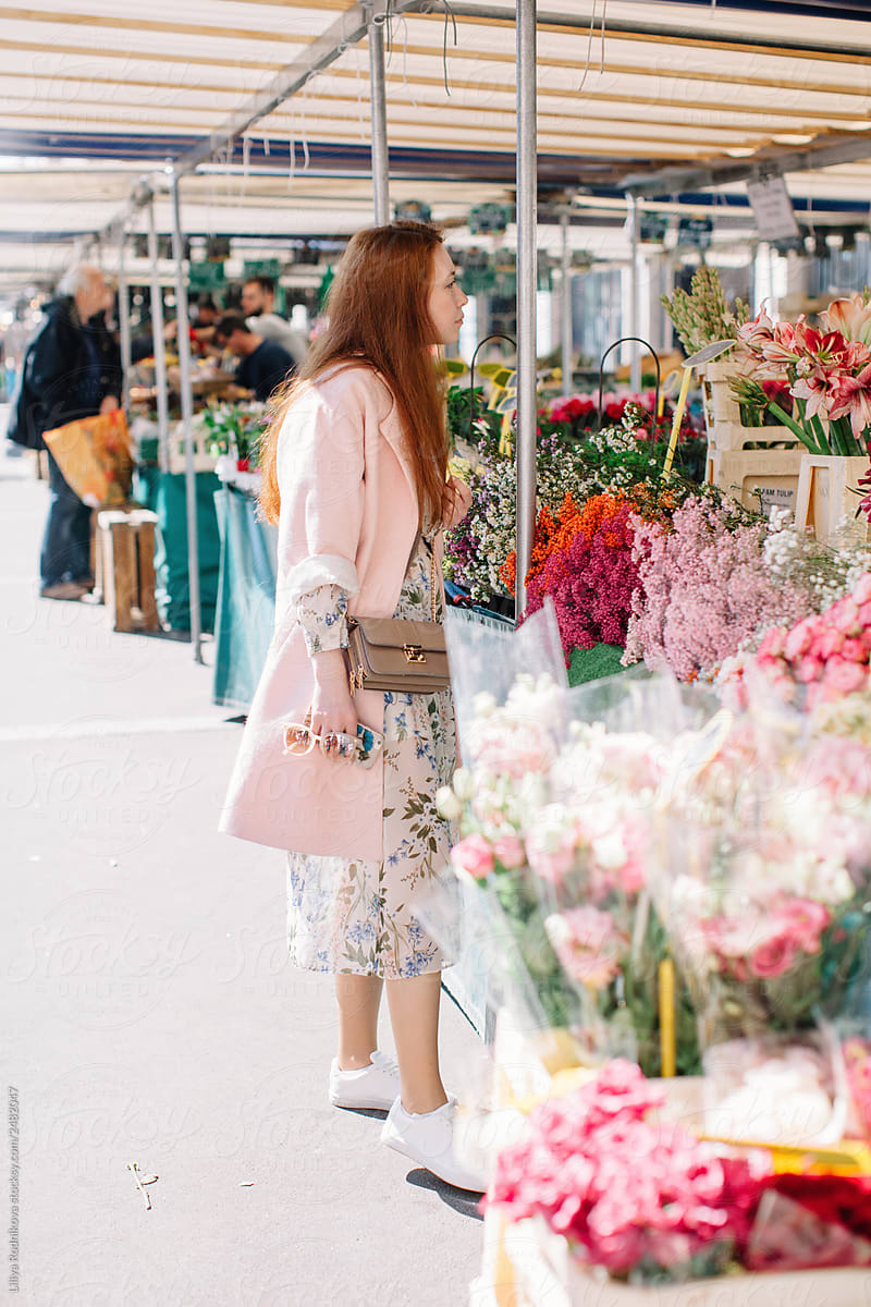 Redhead woman walking by the open market and choosing flowers