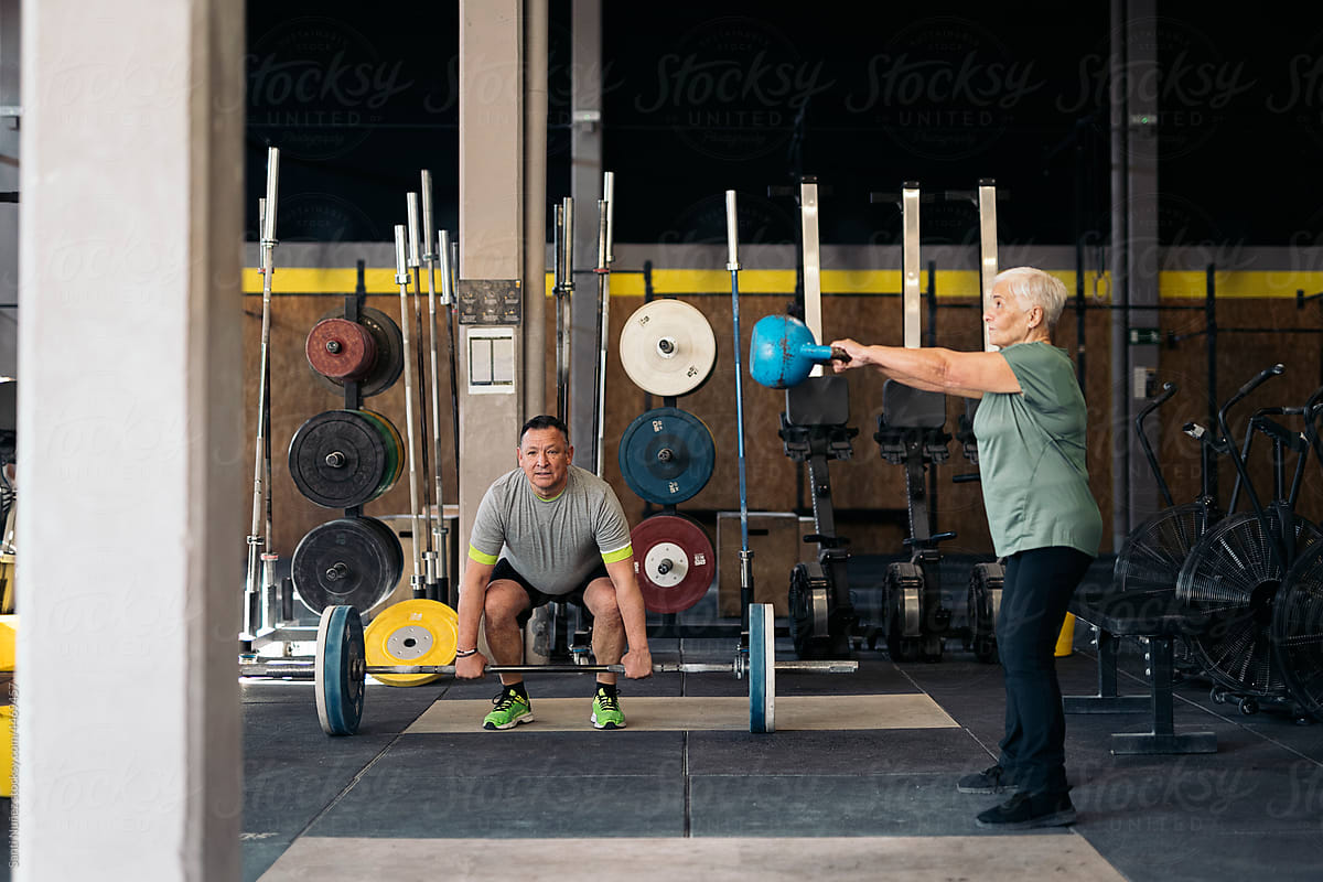 Mature man and woman exercising with weights in gym