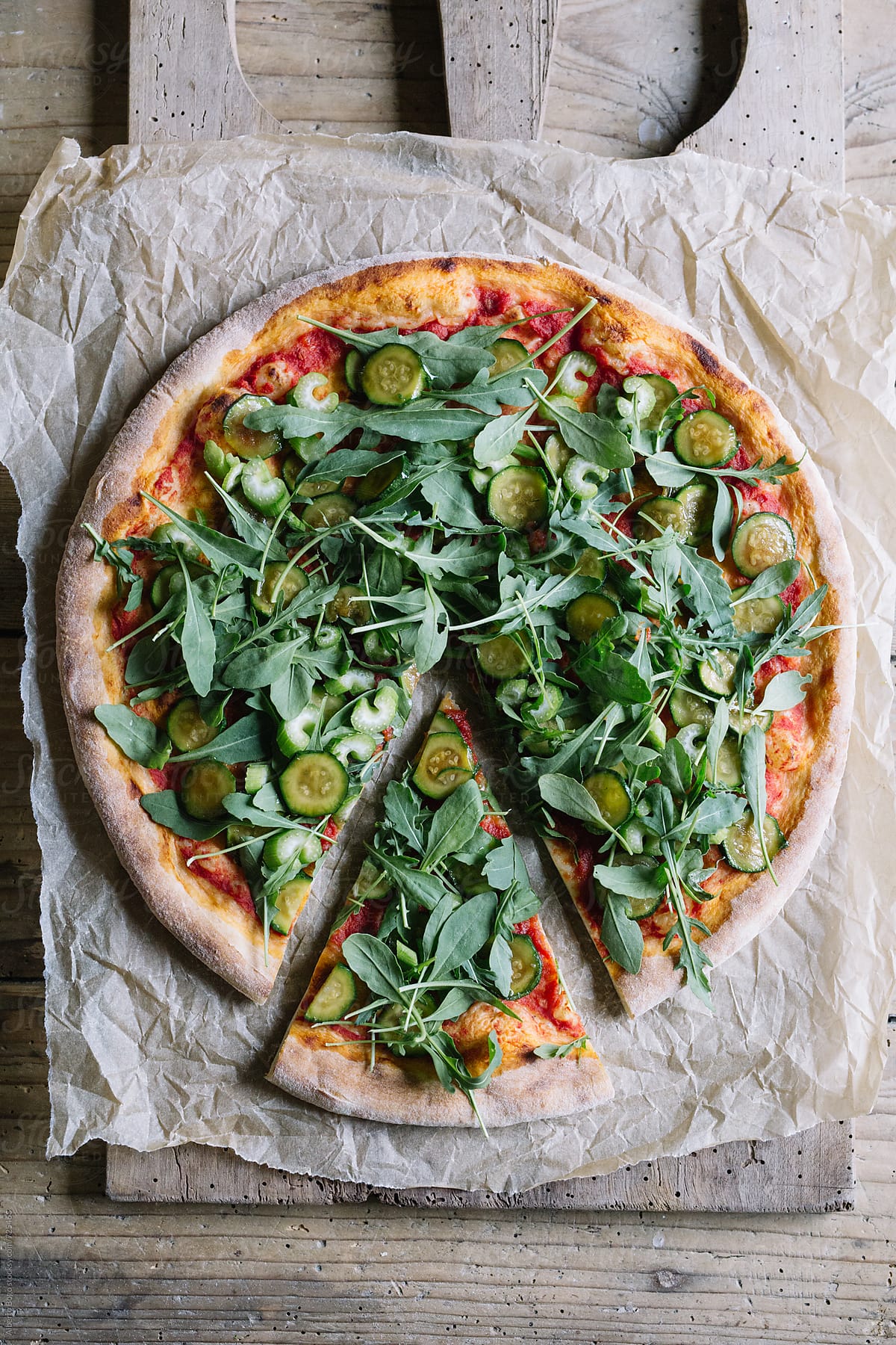 Sliced italian pizza with courgette and arugula on wooden table