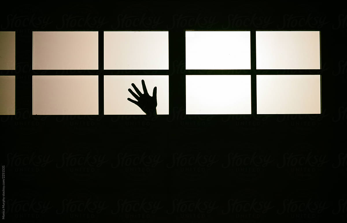 Silhouette of creepy hands in window at night