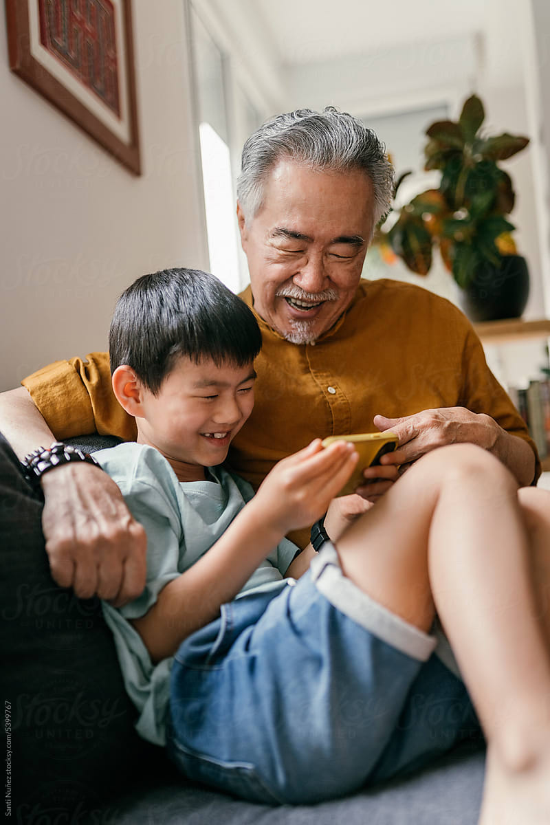 Chinese grandfather and grandson enjoy phone game.