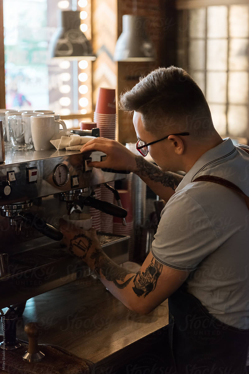 Hipster bartender brewing coffee with machine