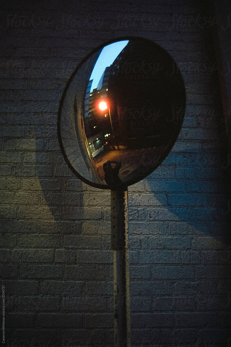 Alley mirror with anonymous person and reflections
