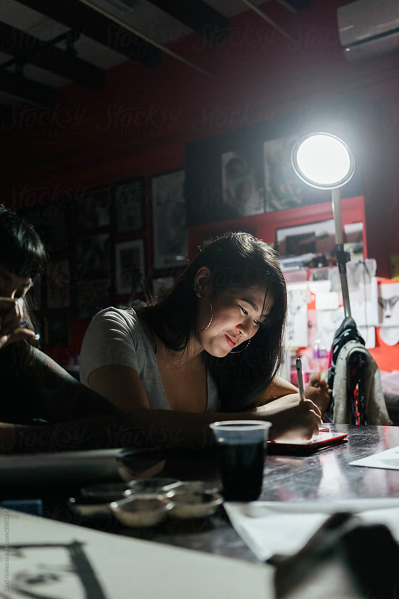 Group of professionals tottooers designing tattoos in studio