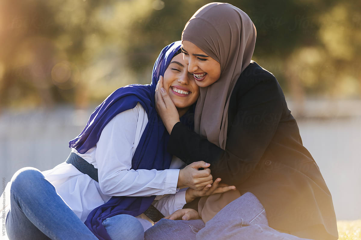 Happy Muslim women in hijab hugging and caressing a friend