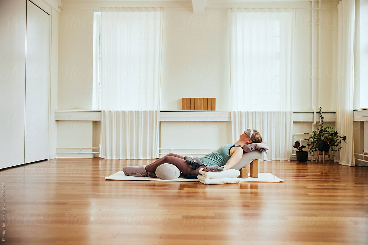 Woman practicing restorative yoga with bolsters