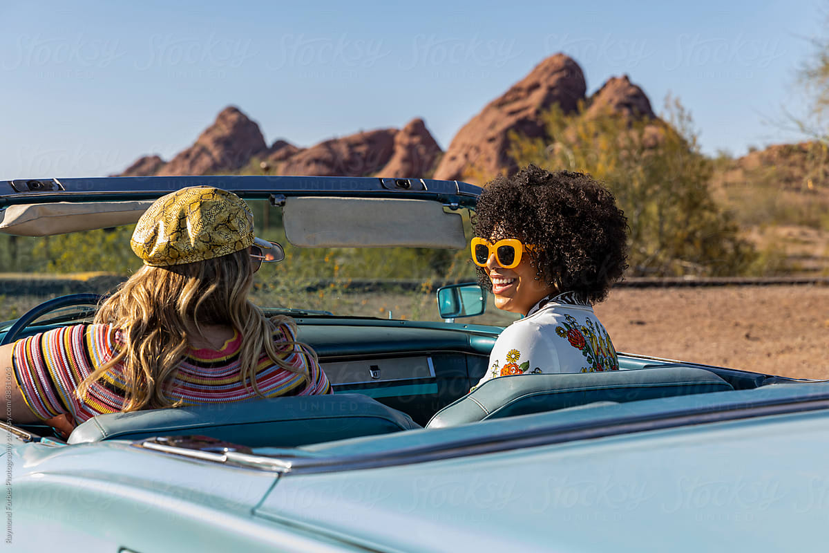 Portrait of Happy Friends Talking in Vintage car on road trip