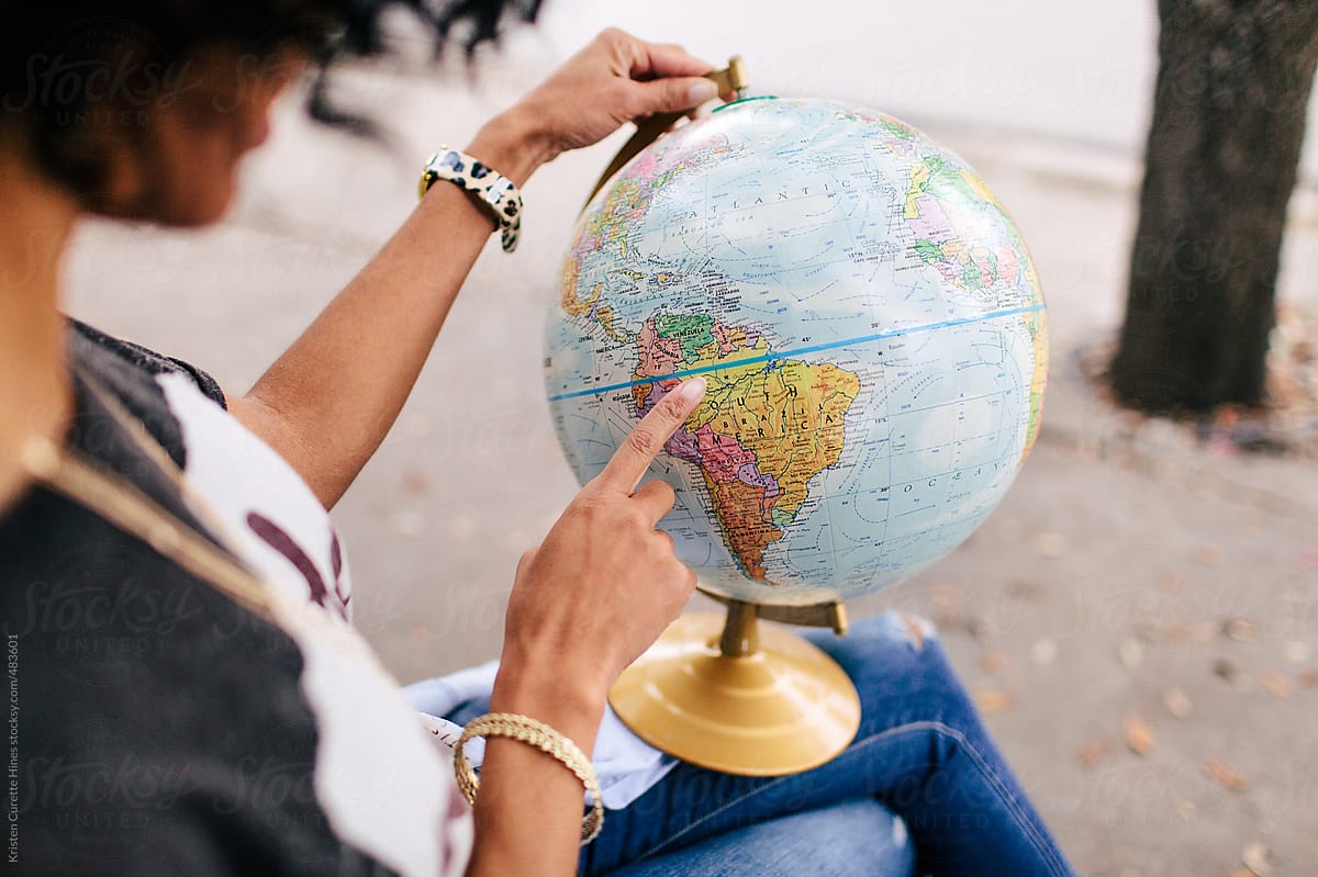 A woman pointing at a location on a world globe