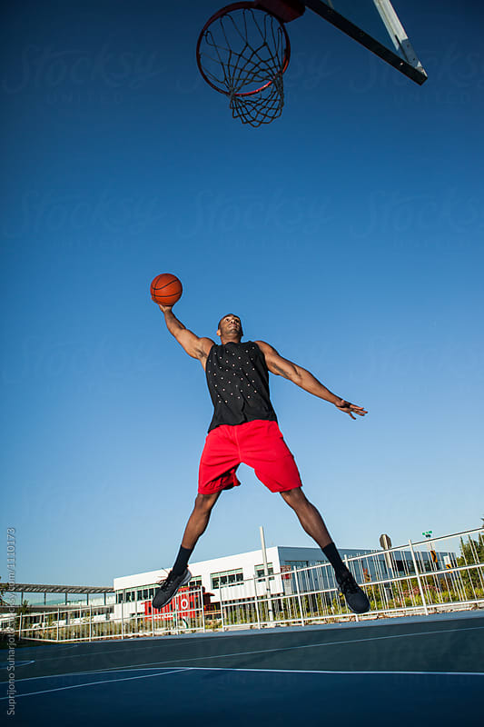 African American man dunking a basketball on an outdoor court