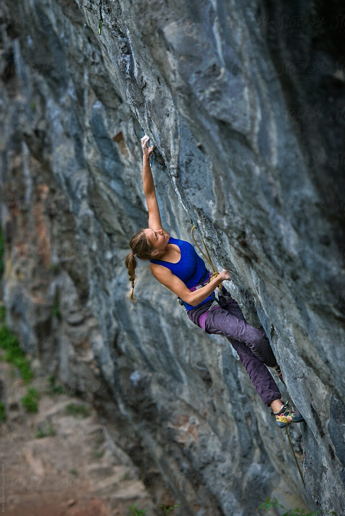 Female climber stretching to reach a hand hold