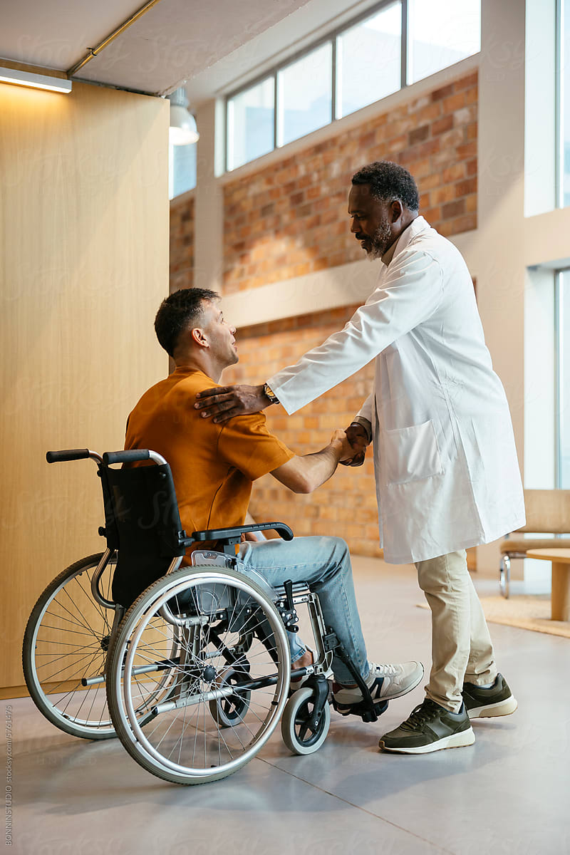 Doctor and man in wheelchair greeting each other at hospital