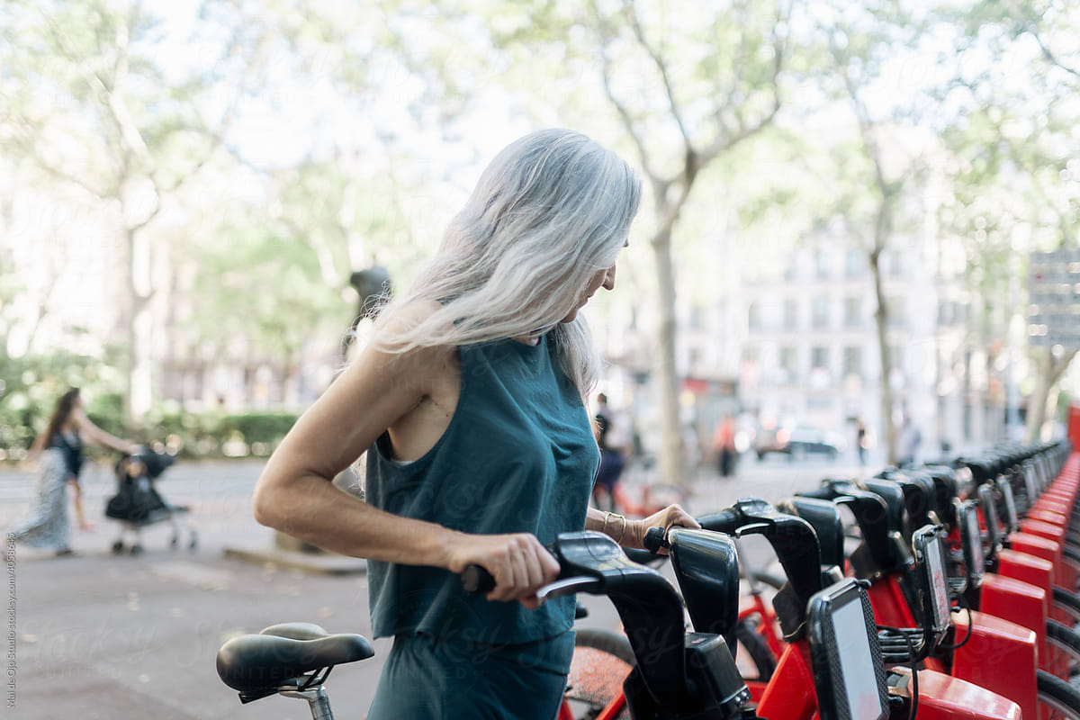 Grey-haired woman picking up a rental bike