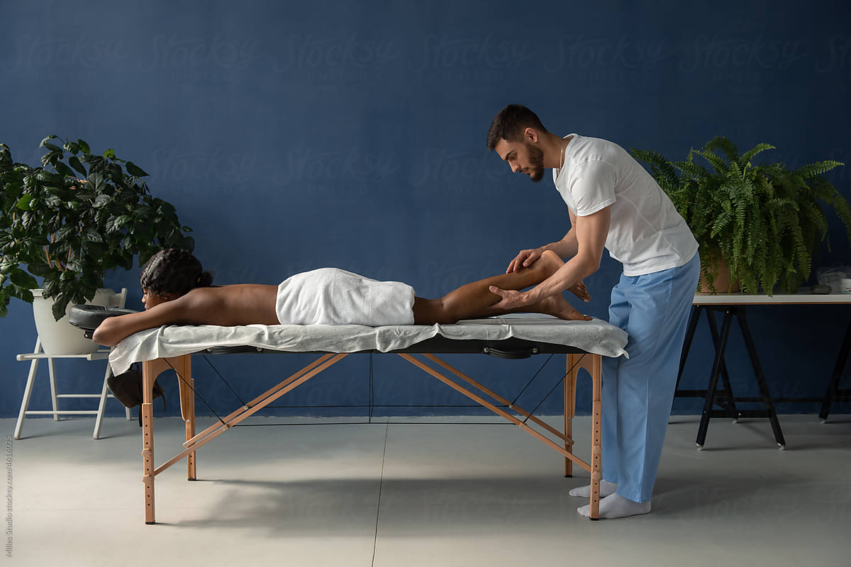 Masseur massaging leg of black woman