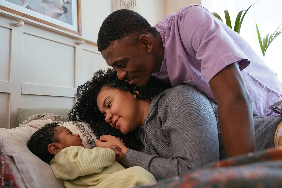 Gentle black couple looking at baby on bed