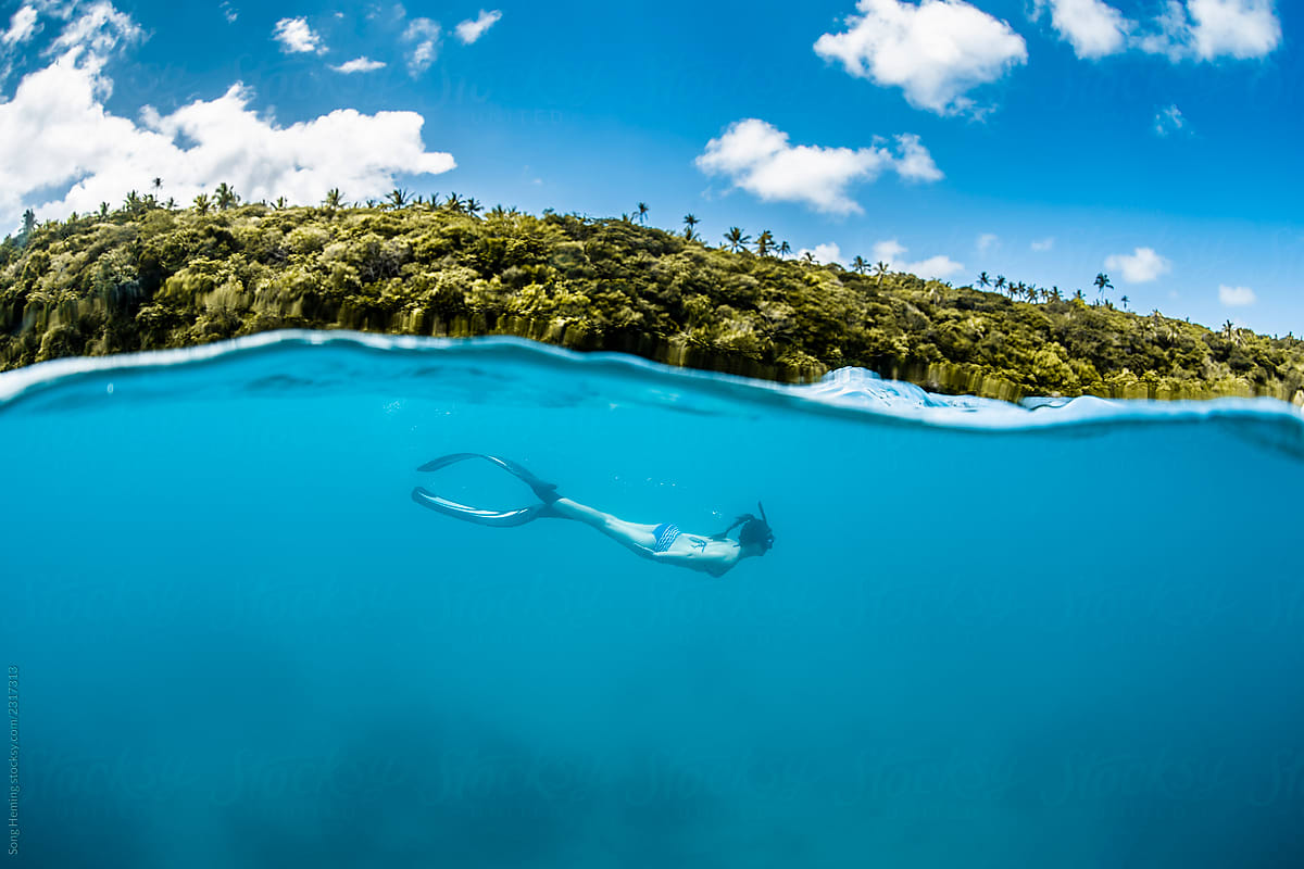 Half underwater seascape with female snorkeling diver with bikini