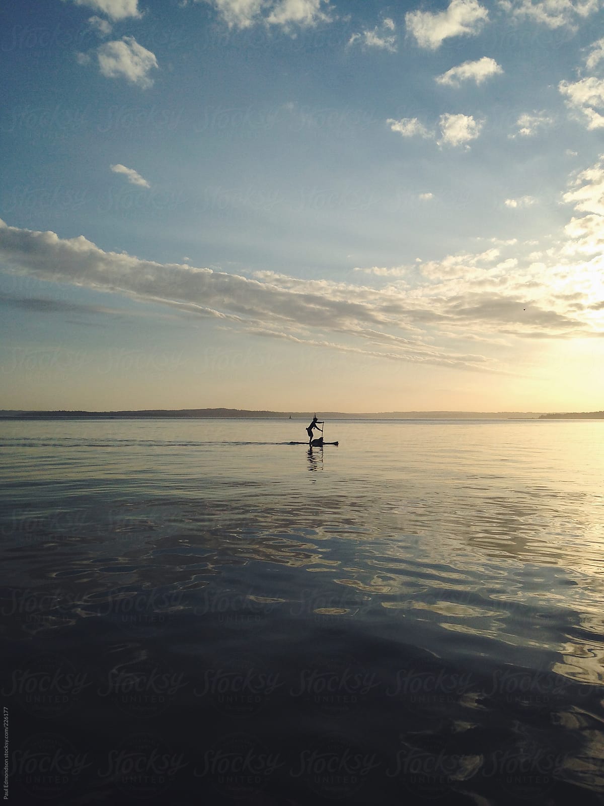 Man stand up paddling with dog at dusk