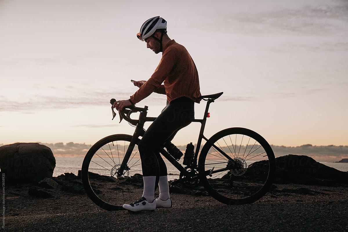 Cyclist checking his phone at sunset