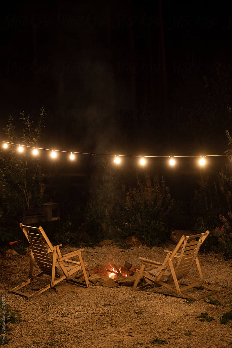 Deckchairs and bonfire under light garland at night