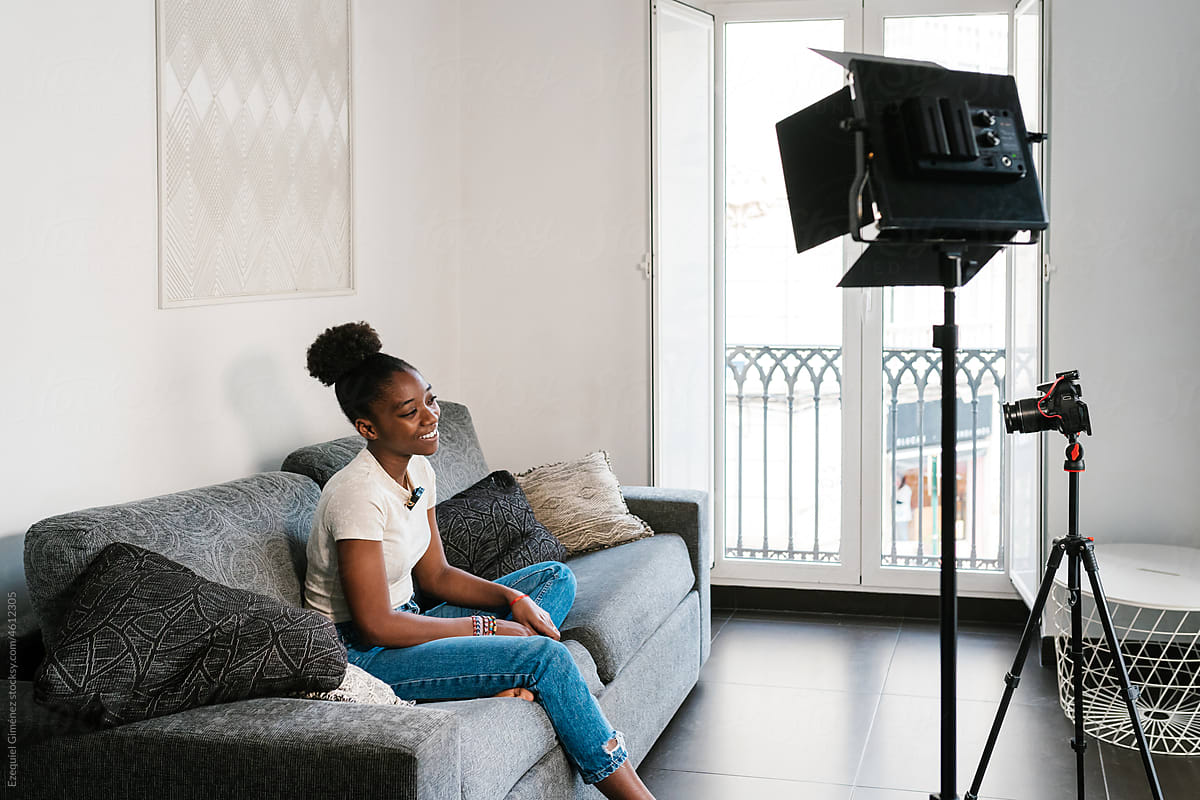 Black teen blogger recording video on sofa